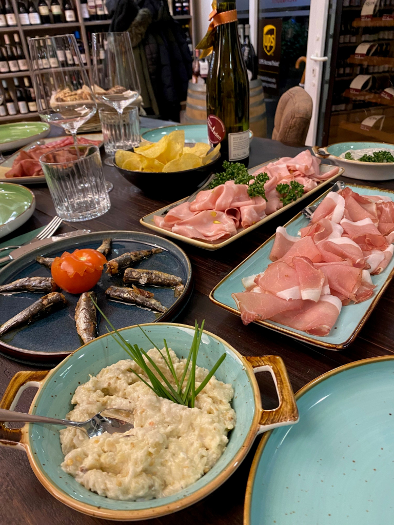 Gedeckter Tisch mit Schinken, Sardinen und Dips bei einer Weinrunde
