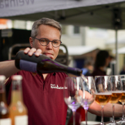 Arno Steguweit schenkt am Weinstand Rosé in eine Reihe Gläser ein