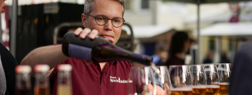 Arno Steguweit schenkt am Weinstand Rosé in eine Reihe Gläser ein
