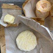 Verschiedene ausgepackte französische Käsesorten mit Weißschimmel- und Rotschmiererinde auf Papierverpackungen