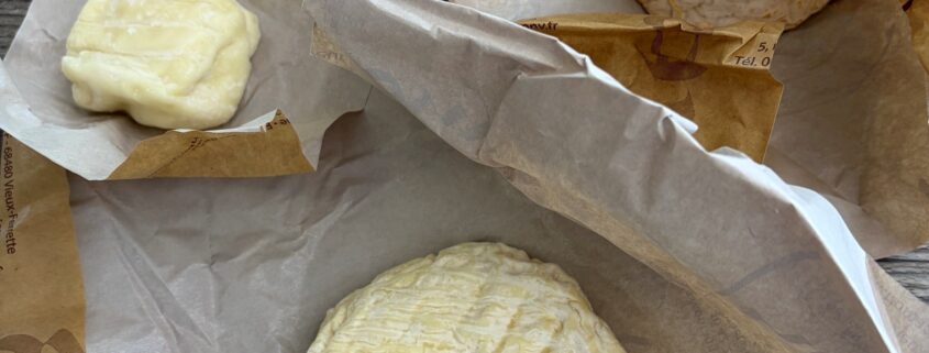 Verschiedene ausgepackte französische Käsesorten mit Weißschimmel- und Rotschmiererinde auf Papierverpackungen