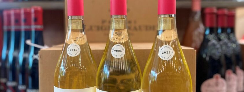 Drei Flaschen Poderi Luigi Einaudi Roero Arneis „Donna Ida“ Jahrgang 2025 stehen im Weinladen auf einem Holztisch